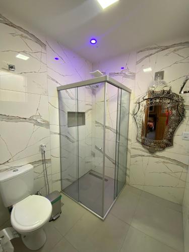 a bathroom with a toilet and a glass shower at Na Trilha da Ostra 2 - Brechó e Antiquário in Brumadinho