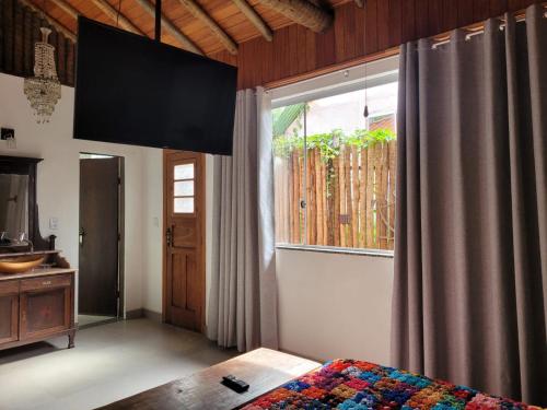 a bedroom with a bed and a large window at Na Trilha da Ostra 2 - Brechó e Antiquário in Brumadinho