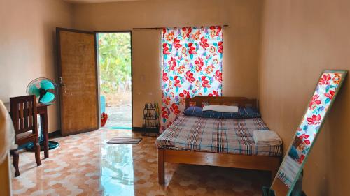 a bedroom with a bed and a sliding glass door at Macabuag Apartment in Narra