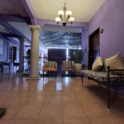 a lobby with purple walls and chairs and a chandelier at Hotel Hacienda Entabladero in Entabladero