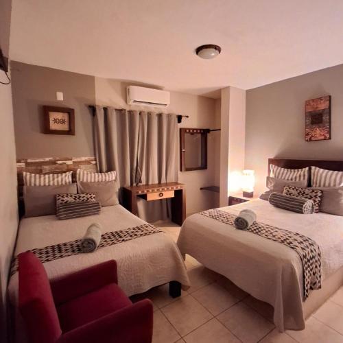 a bedroom with two beds and a red couch at Hotel Hacienda Entabladero in Entabladero