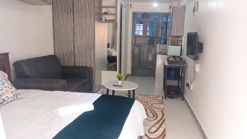 a bedroom with a bed and a couch and a table at Franliz Apartments in Nairobi