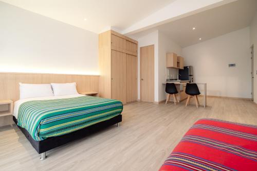 a bedroom with a bed and a desk and a kitchen at Hotel Estar in Manizales