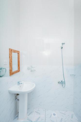 a white bathroom with a sink and a shower at Roots and Waves in Zanzibar City