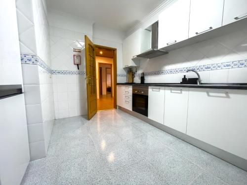 a kitchen with white cabinets and a wooden door at Apartment near Sintra and Lisbon in Belas