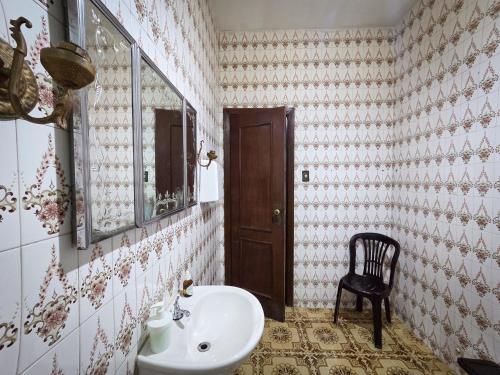 a bathroom with a sink and a mirror and a chair at Vila Mariah Hostel in Belo Horizonte