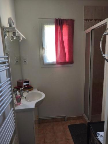 a bathroom with a sink and a window with a red curtain at Pavillon in Saint-Berthevin-sur-Vicoin