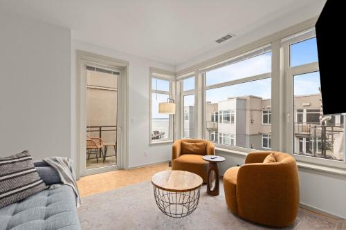 a living room with a couch and chairs and windows at Seattle Waterfront Condo - Walk Up Steps to Pike Place in Seattle