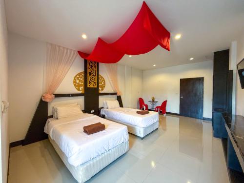 two beds in a hotel room with a red canopy at POR SAHA Hotel Ramkhamhaeng 100 in Bang Kapi