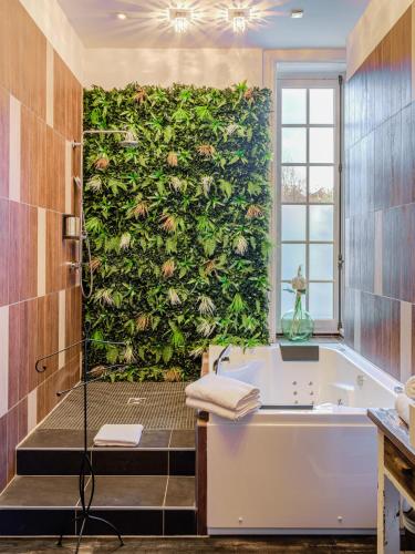 a bathroom with a green wall with a bath tub at Hotel Ô Château in Hayange