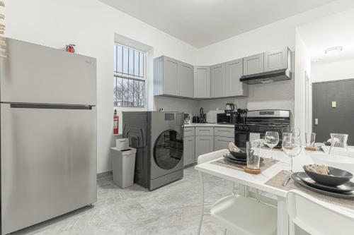 a kitchen with a refrigerator and a table with wine glasses at Modern Comfort 2BR with Washer & Dryer Near Subway & LGA in Corona