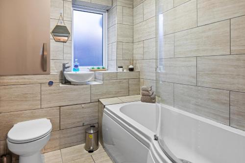 a bathroom with a tub and a toilet and a sink at Forest View- Oasis Mural -Didsbury Zen Sleeps 10 in Manchester