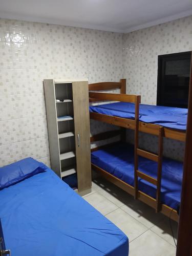 two bunk beds in a room with blue sheets at Ed.fragatas residence in Bertioga