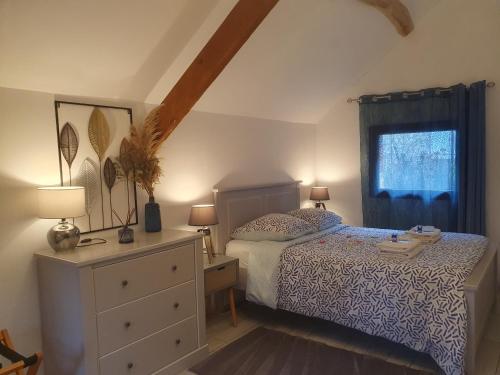 a bedroom with a bed and a dresser and a window at Gîte Les Fourmilières in Ligny-le-Ribault