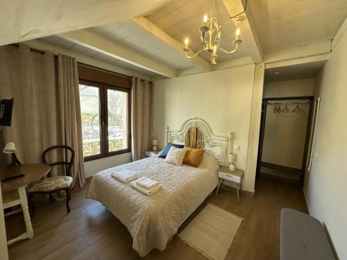 a bedroom with a bed and a table and a window at Casa Rural Belladona in Valdeprados