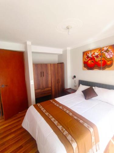 a bedroom with a large white bed and wooden floors at Residencial SKD in Puno