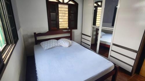 a small room with a bed and two windows at Recanto do mar in Caraguatatuba