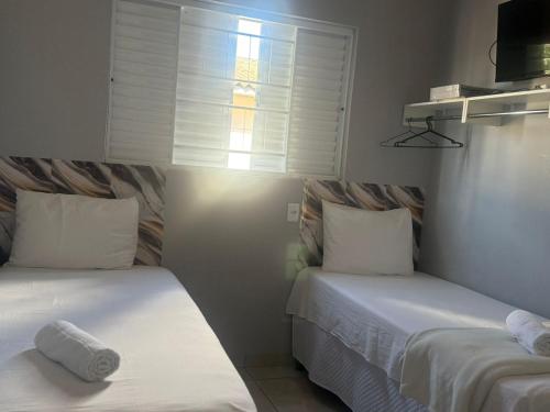 two beds in a small room with a window at Amazon LOFT 08 in Sorriso