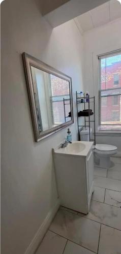 a bathroom with a sink and a mirror and a toilet at Charm's City Cozy Studio in Baltimore