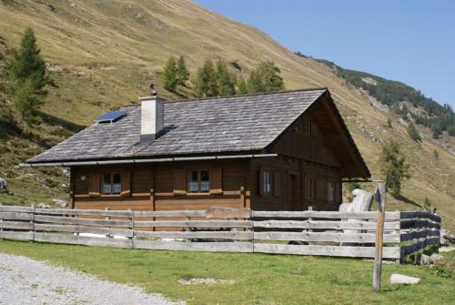 a wooden cabin with a fence in front of a hill at Fröschlhütte in Oberpirkach