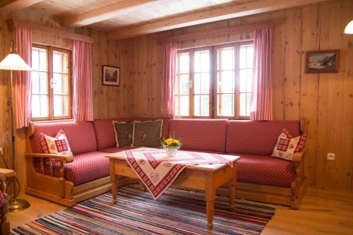 a living room with a red couch and a table at Ferienhütte Windlegern in Neukirchen