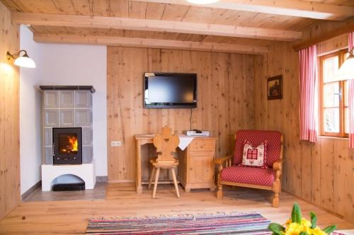 a room with a fireplace and a tv and a chair at Ferienhütte Windlegern in Neukirchen