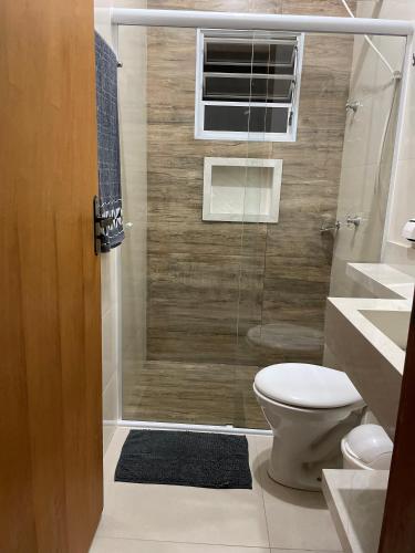a bathroom with a shower with a toilet and a window at Recanto dos Ipês a 4 min do Moinho in Holambra