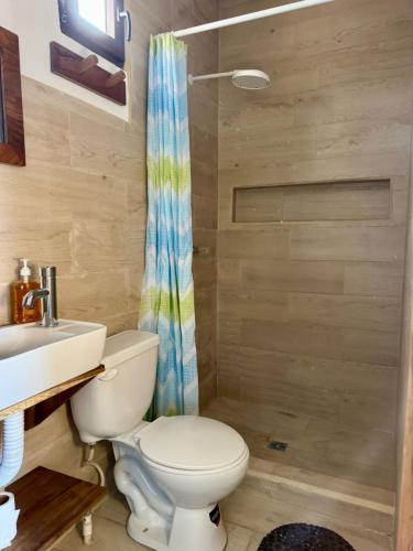 a bathroom with a toilet and a sink and a shower at Secret Garden Cottage in El Naranjo