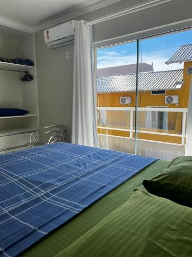 a bedroom with a bed and a large window at Residencial Costa Marfim in Bombinhas