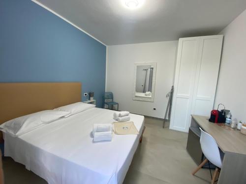 a bedroom with a large white bed and a desk at DOMO DE MARIA in San Teodoro