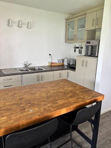 a kitchen with white cabinets and a wooden table at Coastal Guest Suite near Fishermans Cove in Whangaparaoa