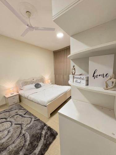een witte slaapkamer met een bed en een vloerkleed bij Spacious Suite in Jazīrat as Sāyah