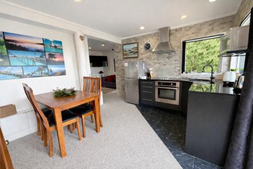 a kitchen with a wooden table and a dining room at Cosy Raglan Studio - Walk to Beach and Village - Roberts St - Studio Downstairs in Raglan