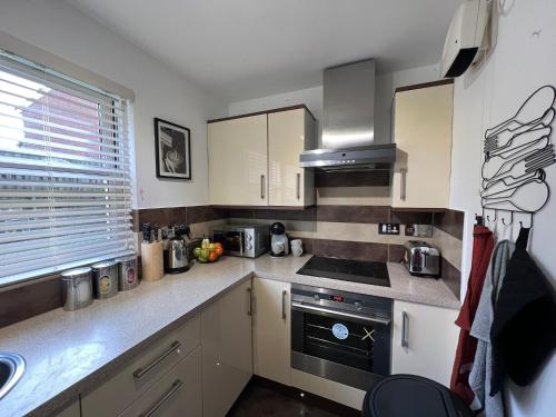 a kitchen with white cabinets and a stove top oven at 2 Bedroom Apartment 11 Minutes From Stansted Airport in Great Dunmow