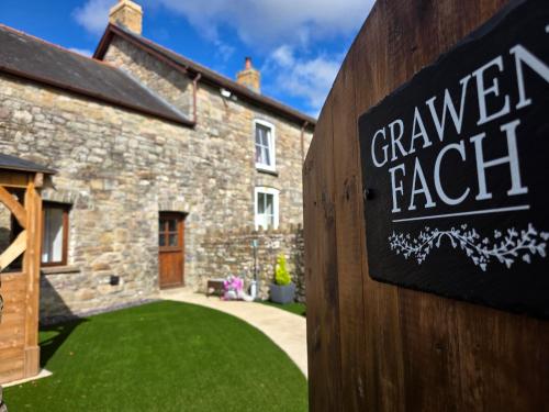 a sign in front of a stone house at Grawen Fach in Cefn-coed-y-cymmer