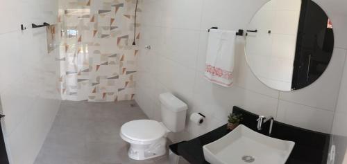 a bathroom with a toilet and a sink and a mirror at Espaço Real in Manhã