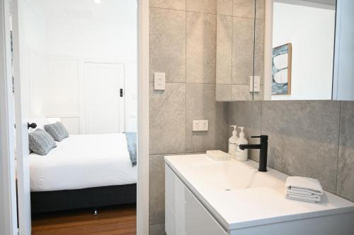 a bathroom with a white sink and a bed at Soluna House in Byron Bay
