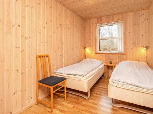 two beds in a room with a table and a window at 8 person holiday home in Læsø in Læsø