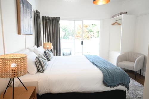 a white bedroom with a large bed and a chair at Soluna House in Byron Bay