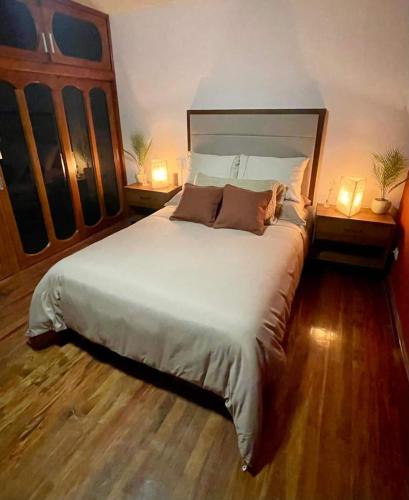 a bedroom with a large white bed with two lamps at Casa Sosa in Zacatlán