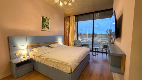 a bedroom with a bed and a desk and a window at Villa #40, Ambassadori Kachreti Golf Resort in Kachretʼi