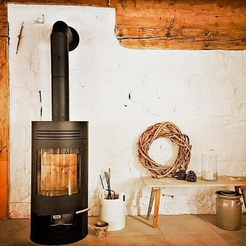 a black fireplace in a room with a table at Lovingly Restored Half-Timbered House From 1684 in Großschönau