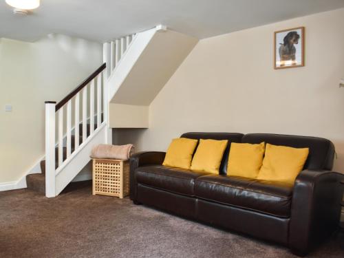 a living room with a black leather couch and stairs at Winnies Cottage in Belford