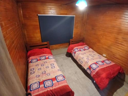 two beds in a small room with a tv at Hospedaje Abiel in El Mollar