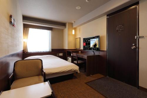 a small hotel room with a bed and a desk at Okayama View Hotel in Okayama