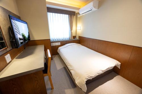 a room with a bed and a desk and a television at Okayama View Hotel in Okayama