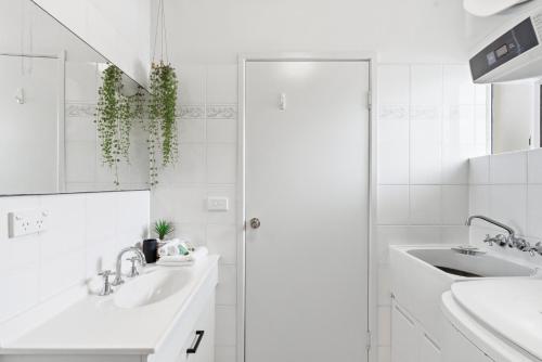 a white bathroom with two sinks and a mirror at Trinity Beach Pacific in Trinity Beach
