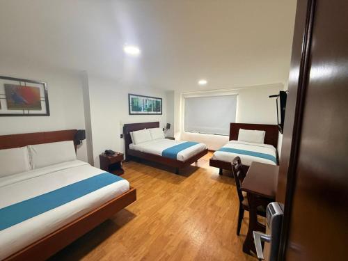 a room with two beds and a table and a desk at Hotel Splendor by Friends Company in Bogotá