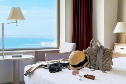 a hotel room with a hat and a camera on a bed at Surfeel Hotel Wakkanai in Wakkanai