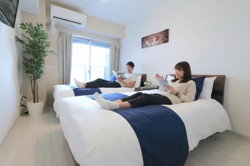 a group of people sitting on beds reading books at Elizabeth Garden Shinsaibashi in Osaka